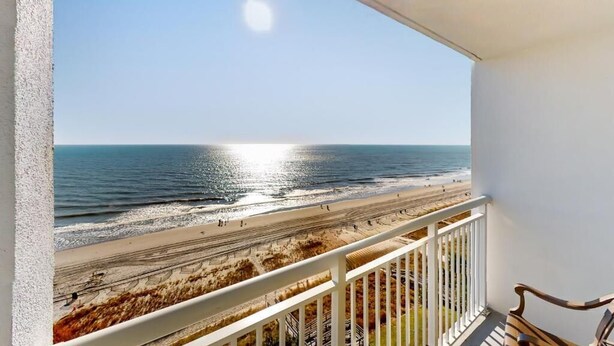 Uma varanda com vista para a praia e o oceano.