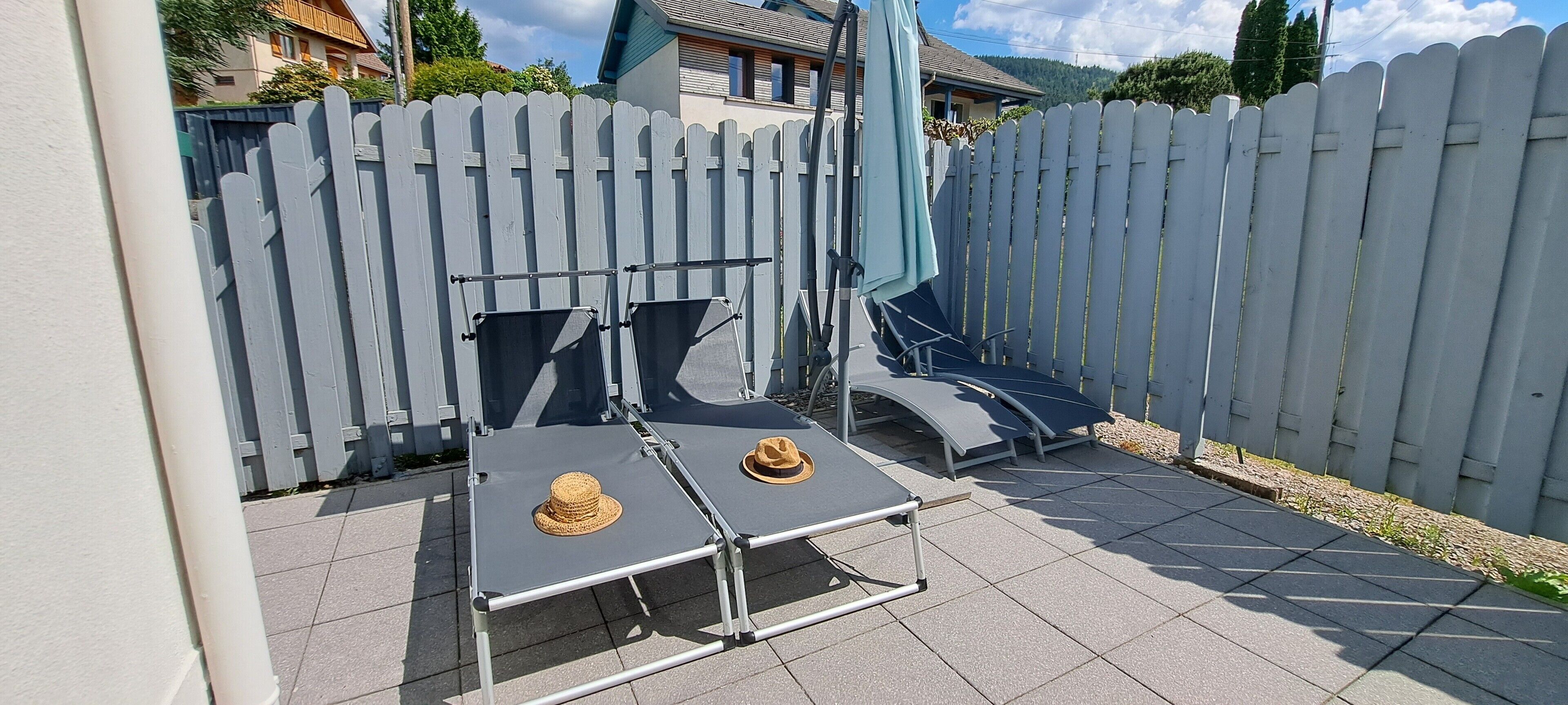 Un patio con dos tumbonas, una mesa y un sombrero sobre la mesa.