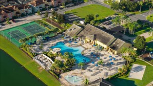 Vue aérienne d’un complexe hôtelier doté d’une piscine, de courts de tennis et d’une plage.