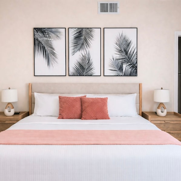 Ein ordentlich eingerichtetes Hotelzimmer mit einem Bett, zwei Nachttischen und drei gerahmten Blätterbildern an der Wand.