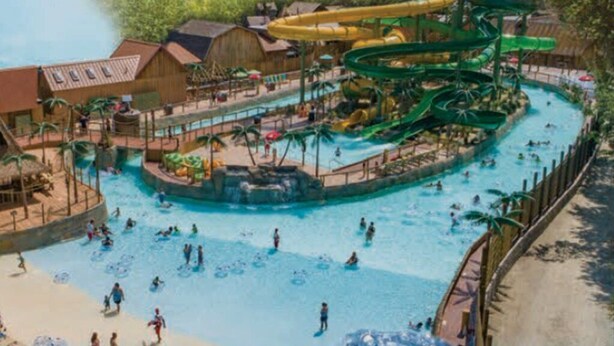 Un parc aquatique doté de plusieurs piscines, de toboggans et d’une structure en bois.