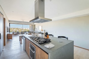 Eine moderne Küche mit einer zentralen Kochinsel, einem eingebauten Backofen und einem großen Fenster mit Blick auf die Stadt.