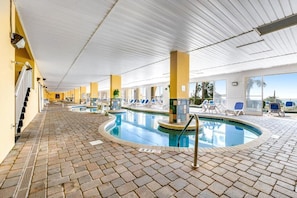 An indoor swimming pool with a tiled floor, sun loungers, and a clear view of the sky. - Charming 2-bedroom apartment with AC in perfect Myrtle Beach Camelot (Myrtle Beach)