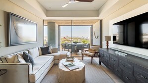 Uma sala de estar moderna com sofá, mesa de centro, TV e uma varanda com mobiliário de exterior.