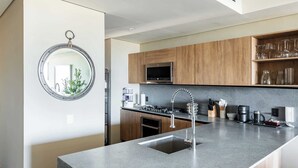 Uma cozinha moderna com ilha central, armários de madeira e micro-ondas embutido.