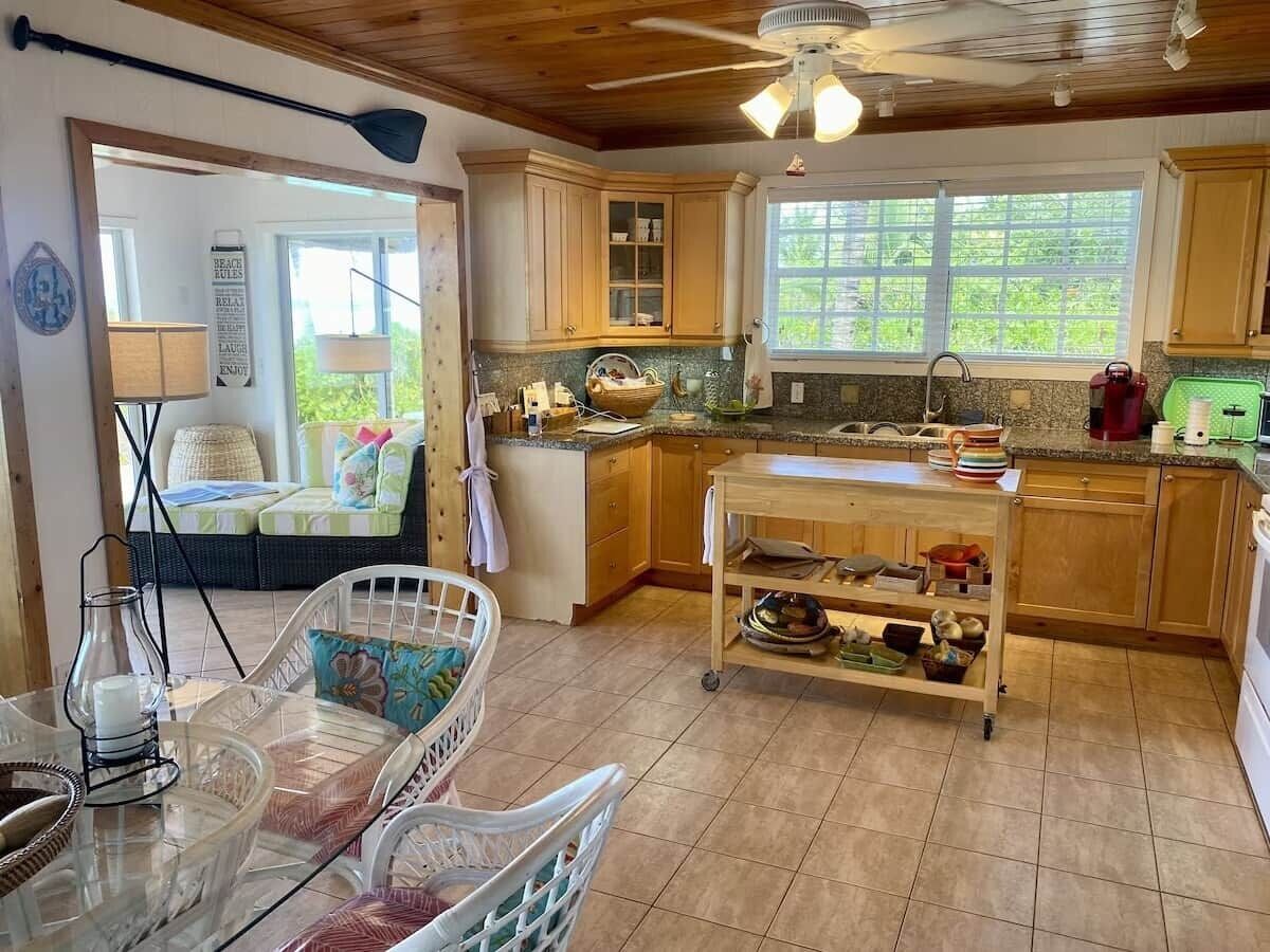 Une cuisine avec des meubles en bois, une fenêtre et un coin repas comprenant une table et des chaises.
