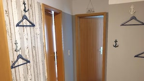 A hallway with a wooden door, a bench, and wall-mounted hangers. - Komfortable Ferienwohnung in Wenkendorf (Fehmarn)