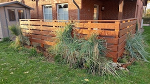 A brick building with a wooden deck and a small shed. - Komfortable Ferienwohnung in Wenkendorf (Fehmarn)