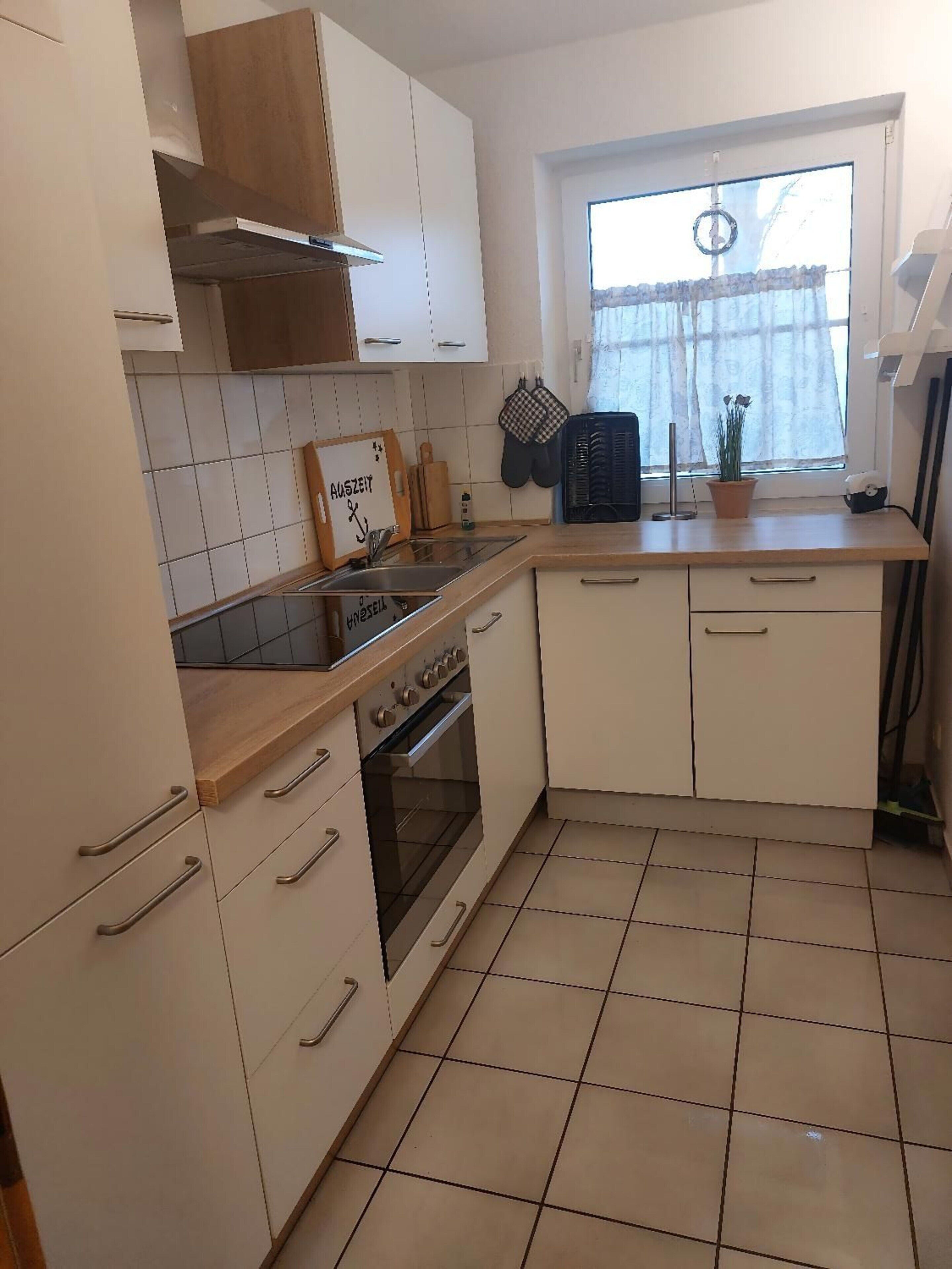 Een keuken met witte kastjes, een houten aanrecht, een fornuis en een raam met uitzicht.