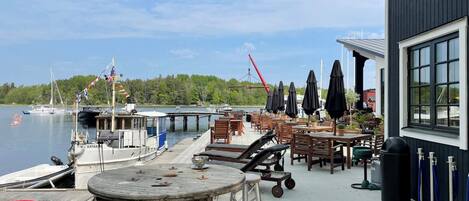 A waterfront restaurant with outdoor seating, a dock with boats, and a view of the lake.