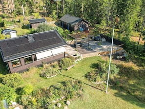 A modern house with a solar panel roof, a wooden deck, and a garden.