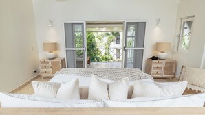 Ein Schlafzimmer mit einem Bett, zwei Nachttischen, einem Fenster und Blick auf Grün.