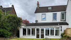 A two-story house with a conservatory, a well-maintained lawn, and a brick chimney. - Large house Drymen Village with Health club access (Drymen)