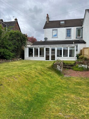 A two-story house with a conservatory, a well-maintained lawn, and a brick chimney. - Large house Drymen Village with Health club access (Drymen)