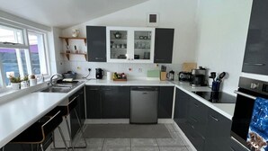 A modern kitchen with dark cabinets, a stainless steel sink, and a built-in dishwasher. - Large house Drymen Village with Health club access (Drymen)