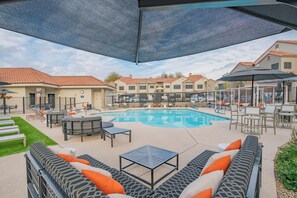 A pool area with lounge chairs, a table, and umbrellas. - 2Min to Kierland | Heated pool | Dining | Shopping (Scottsdale)