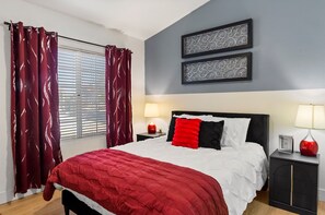A bedroom with a bed, two bedside tables, a window with curtains, and two wall-mounted decorative items. - Serene TPC Gem | Dining & Shopping Nearby+Walkable (Scottsdale)