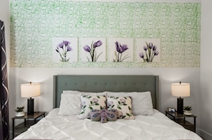 A neatly made bed with a floral pillow, a green upholstered headboard, and a wall with a green leafy pattern. - 2BR TPC Retreat Near Mayo Clinic & Desert Ridge (Scottsdale)