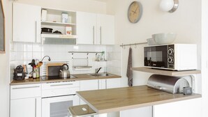 Ett kök med vita skåp, en mikrovågsugn, en vattenkokare och en högtalare från JBL.
