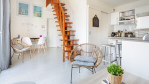 En modern inredning med en spiraltrappa, möbler i rotting, ett köksområde och en matplats.