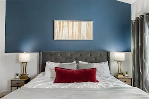 A neatly made bed with a red pillow, a tufted headboard, and a framed artwork above it. - Near TPC|Heated Pool| Near Shops | Dine | Museums (Scottsdale)