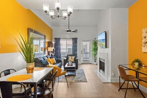A modern living room with a sofa, dining table, and chairs. There is a fireplace and a ceiling fan. - Quiet Retreat Near Dining| Shops| Nightlife | Golf (Scottsdale)