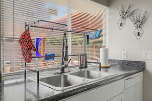 A kitchen with a stainless steel sink, a dish rack, and a window with blinds. - 3BR w/ Private Pool + Backyard Retreat-Perfect for Families -Glendale, AZ (Glendale)