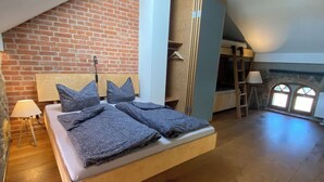 A loft bedroom with a sloped ceiling, exposed brick walls, a wooden bed, and a skylight. - Duplex Flat With a Fireplace in a Historic Vaulted Building (Grossharthau)