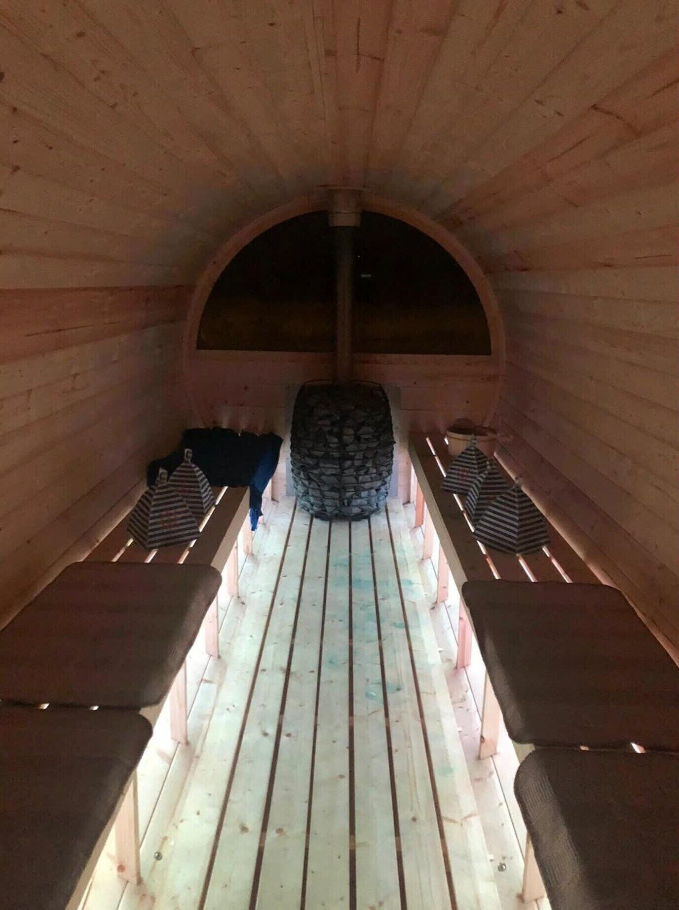 Un intérieur en bois avec des bancs et une structure en pierre au centre.