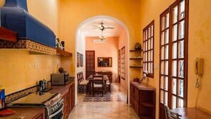 A kitchen with a central island, a dining area with chairs, and a ceiling fan. - Chez David magnificent colonial retreat (Mérida)