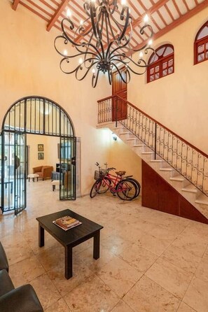 A spacious lobby with a staircase, a chandelier, a bicycle, and a coffee table. - Chez David magnificent colonial retreat (Mérida)