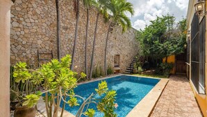 A swimming pool with a stone wall, a staircase, and potted plants. - Chez David magnificent colonial retreat (Mérida)