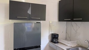 Una cucina moderna con frigorifero in acciaio inossidabile, pensili neri, una macchina da caffè e una schiena di marmo.