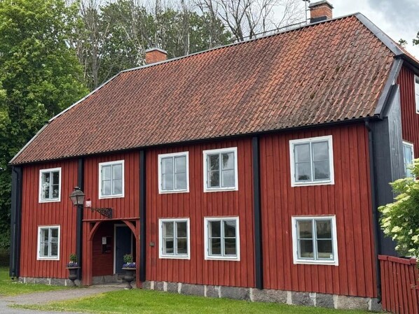A red wooden building with multiple windows and a sloped roof.