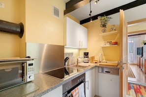 Una cocina moderna con electrodomésticos de acero inoxidable, armarios blancos y horno empotrado.