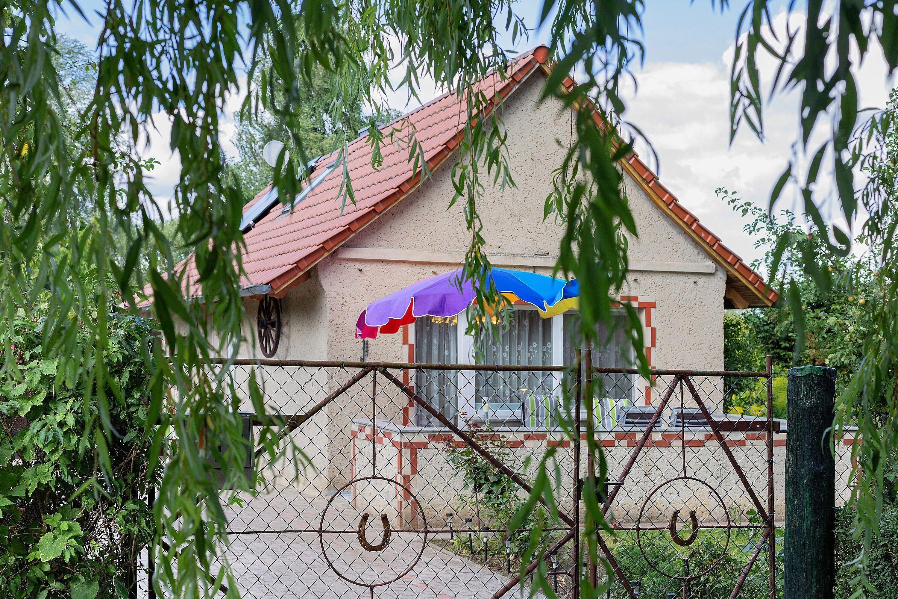 Ein Haus mit rotem Dach, einem Zaun aus Maschendraht und einer Hufbeschlag-Dekoration.