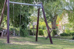 Columpios en un parque con estructura metálica, cadenas y asiento de madera.