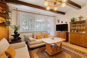 Ein gemütliches Wohnzimmer mit einer Couch, einem Couchtisch, einem Fernseher und einer Vitrine mit Dekoration.