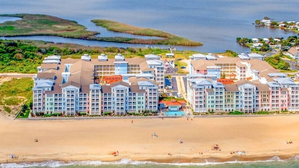 Um hotel à beira-mar com vários edifícios, uma praia de areia e uma extensa área de água.