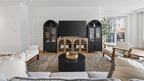 Uma sala de estar moderna com uma televisão de tela plana, dois armários, uma mesa de centro e um sofá.