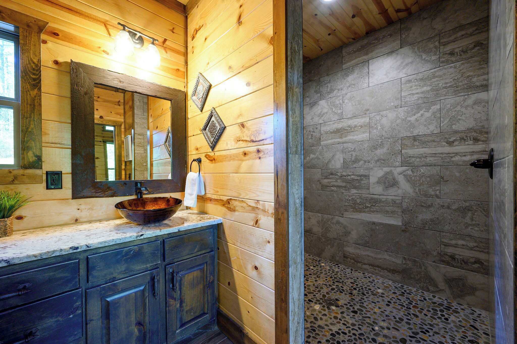 Een houten interieur met een houten wastafel, een spiegel en een douche met stenen tegels.