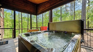 Un bain à remous sur une terrasse en bois, avec vue sur la forêt.