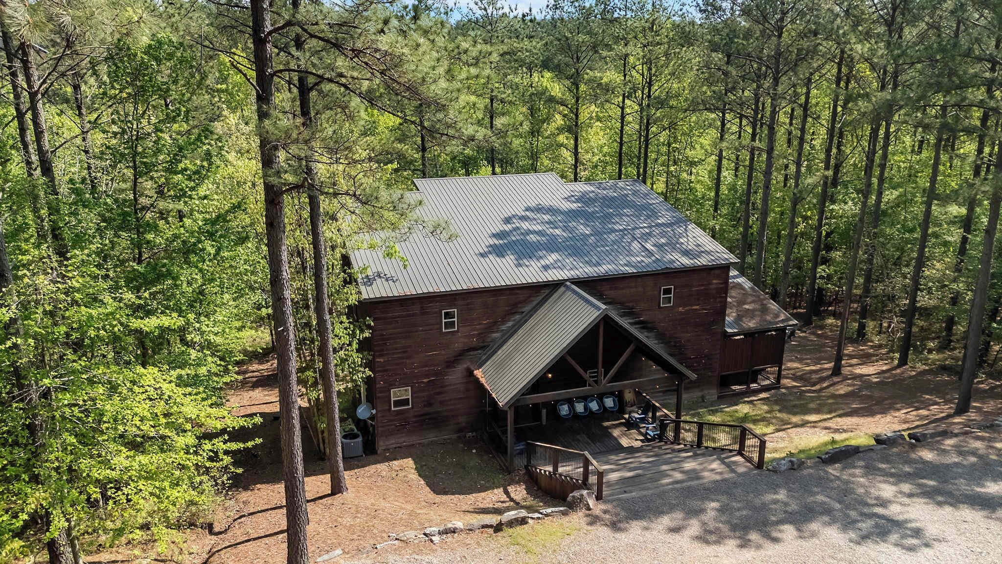 A rustic wooden cabin with a metal roof, surrounded by a forest.