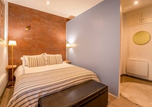 Ein Schlafzimmer mit einem Bett, Nachttischlampen, einem runden Spiegel und einem Heizkörper.