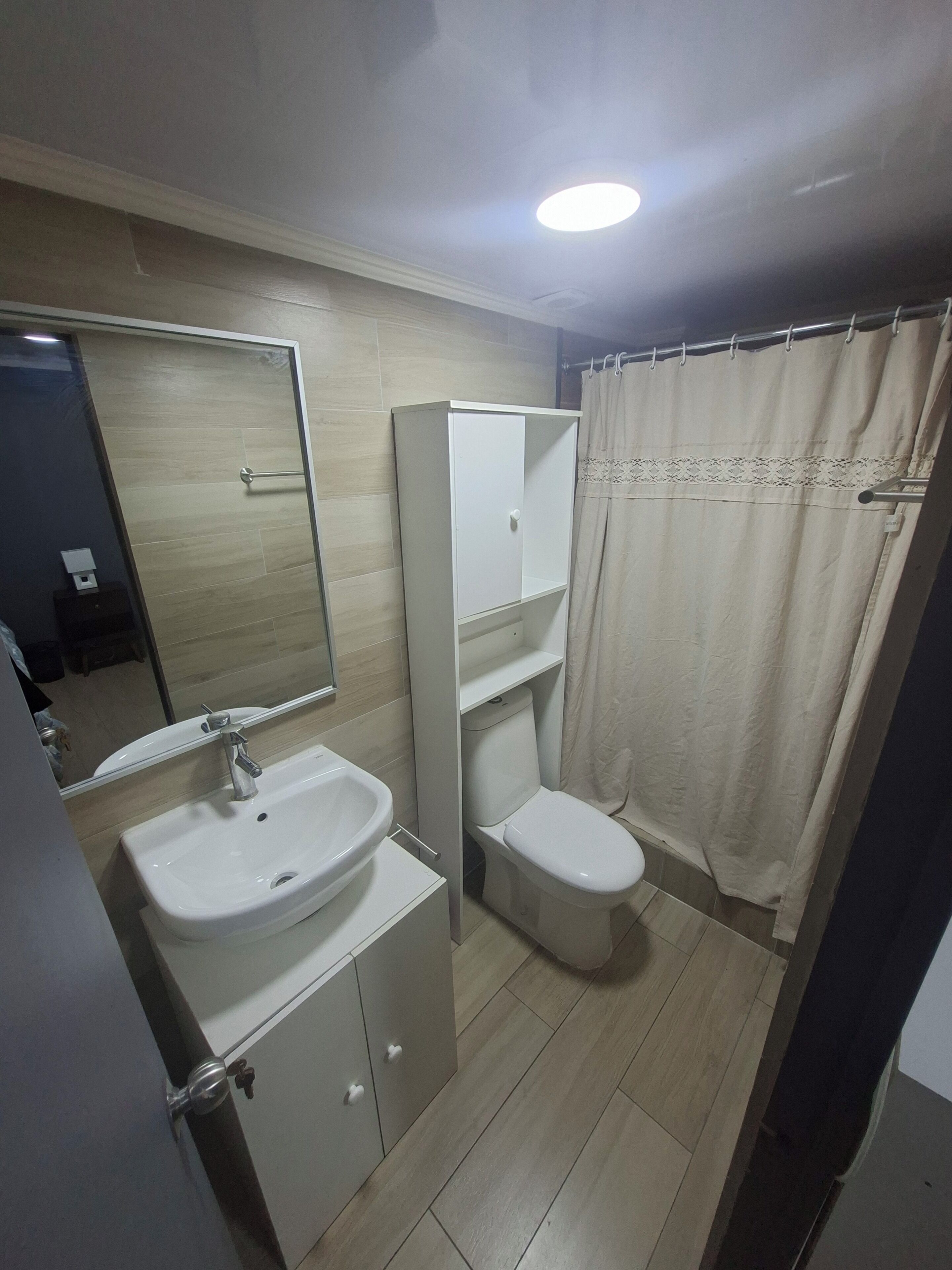 A bathroom with a sink, toilet, and mirror.