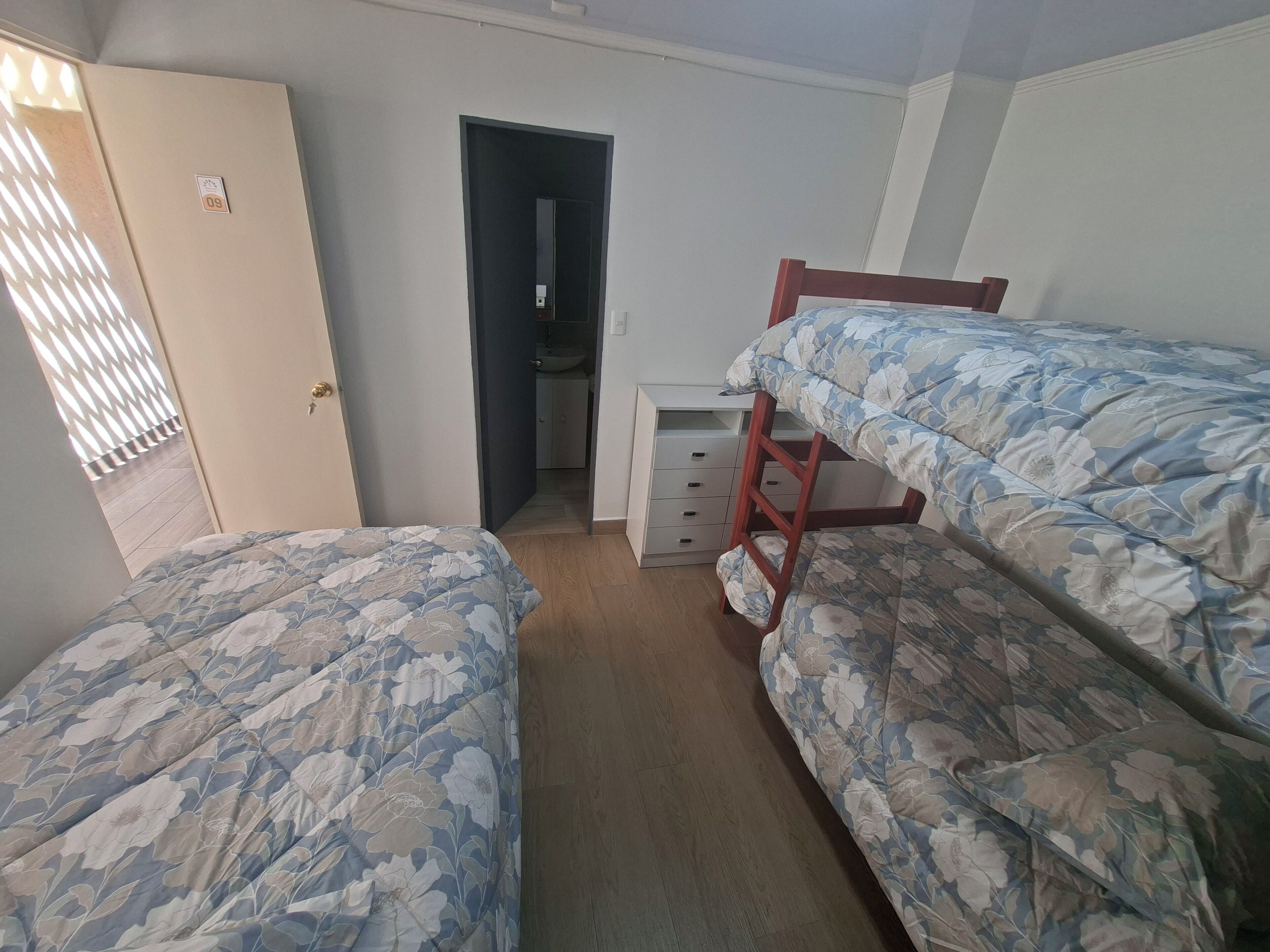 A bedroom with two beds, a desk, a wardrobe, and a bathroom.