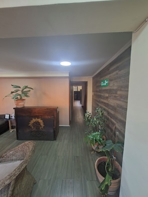 Un pasillo con mostrador de recepción, plantas en macetas y una pared de madera.