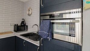 A modern kitchen with a built-in microwave, kettle, and stainless steel oven. - 38 St Margarets (Dover)