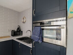 A modern kitchen with a built-in microwave, kettle, and stainless steel oven. - 38 St Margarets (Dover)