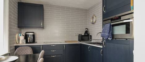 A compact kitchen with dark cabinetry, a coffee maker, a microwave, and a toaster.